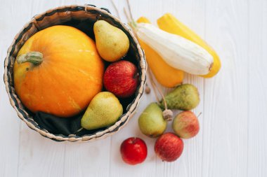 Merhaba sonbahar kavramı ve sonbaharda hasat. Düz yatıyordu. Kabak ve elma ve armut beyaz ahşap arka planda, üstten görünüm ile şık hasır sepet içinde kabak