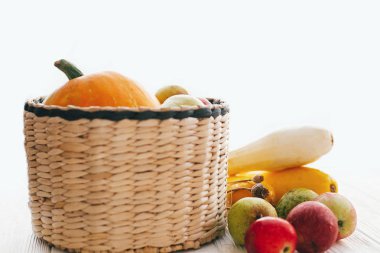 Merhaba sonbahar kavramı ve sonbaharda hasat. Kabak ve elma ve armut beyaz ahşap arka planda ışık, metin için yer ile şık hasır sepet içinde kabak. Şükran günün kutlu olsun