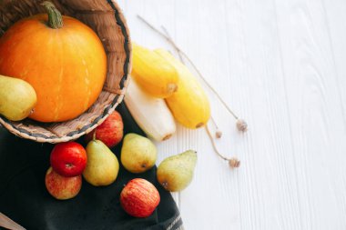 Merhaba sonbahar kavramı ve sonbaharda hasat. Kabak ve elma ve armut beyaz ahşap arka planda ışık, metin için yer ile şık hasır sepet içinde kabak. Şükran günün kutlu olsun