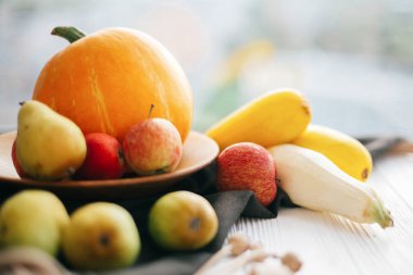 Merhaba sonbahar kavramı ve sonbaharda hasat. Kabak ve elma ve armut keten önlük Beyaz ahşap masa ışık üzerinde şık ahşap plaka kabak. Şükran günün kutlu olsun