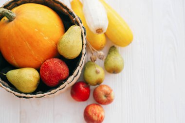 Merhaba sonbahar kavramı ve sonbaharda hasat. Düz yatıyordu. Kabak ve elma ve armut beyaz ahşap arka planda, üstten görünüm ile şık hasır sepet içinde kabak