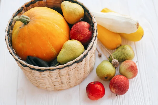 Merhaba sonbahar kavramı ve sonbaharda hasat. Kabak ve elma ve armut beyaz ahşap arka planda ışık, metin için yer ile şık hasır sepet içinde kabak. Şükran günün kutlu olsun