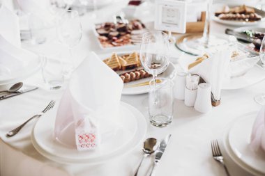 lüks restoranda düğün için catering. şık düğün masa yemek, gümüş çatal bıçak takımı, boş gözlük, Beyaz ipek sandalyeler ve peçeteler. şık düğün tablo ayarı