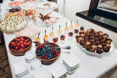 şık şeker bar masa lezzetli kek, kurabiye, meyve ve çilek ile cupcakes. lüks restoranda yemek. modern düğün. tatlı tablo