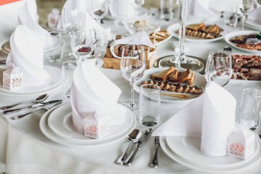 lüks restoranda düğün için catering. şık düğün masa yemek, gümüş çatal bıçak takımı, boş gözlük, Beyaz ipek sandalyeler ve peçeteler. şık düğün tablo ayarı