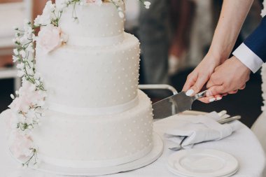 Gelin ve elinde bıçak ve şık kesme damat düğün pastası çiçekli Beyaz. pembe ve beyaz güller ile modern büyük düğün pastası. lüks restoranda yemek. Düğün