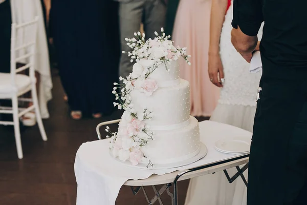 amazing white wedding cake with flowers. modern big wedding cake with pink and white roses. luxury catering in restaurant. wedding reception.