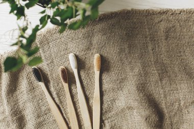 eco natural bamboo toothbrushes on rustic background with greenery. sustainable lifestyle concept. zero waste flat lay. bathroom essentials, plastic free items clipart
