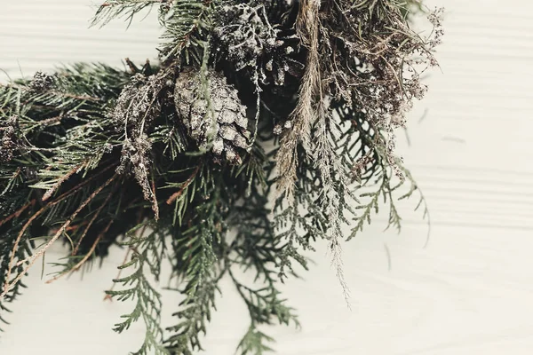 Noel çelenk. çam kozalakları, çam dalları, kar beyaz ahşap kapı üzerinde şık rustik Noel çelenk. metin için yer. El yapımı dekorasyonu kış tatilleri için.