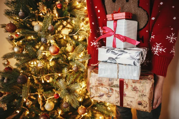 Руки Держат Много Рождественских Подарочных Коробок Золотой Красивой Елке Огнями — стоковое фото