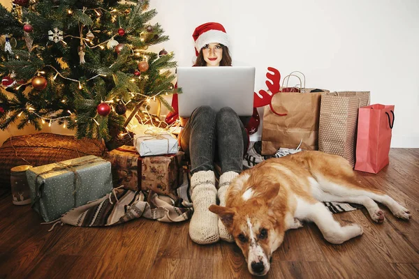 Chica Feliz Sombrero Santa Trabajando Ordenador Portátil Sentado Con Perro —  Fotos de Stock