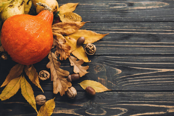 Beautiful Pumpkin with bright autumn leaves, acorns, nuts on wooden rustic table. Happy Thanksgiving concept, flat lay. Space for text. Fall season greeting card. Atmospheric image