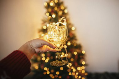 garland ampuller içinde şık vintage cam altın güzel Noel ağacı ışıkları Festival odasında ile arka plan üzerinde tutan el. kış tatili rahat. Noel şerefine.