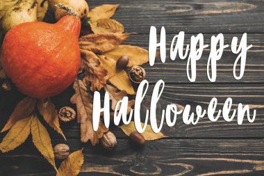 Güzel kabak parlak sonbahar yaprakları, meşe palamutları, ahşap rustik masa fındık ile mutlu Halloween metin, düz yatıyordu. Atmosferik görüntü. Mevsim tebrik kartı.