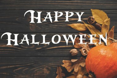 Güzel kabak parlak sonbahar yaprakları, meşe palamutları, ahşap rustik masa fındık ile mutlu Halloween metin, düz yatıyordu. Atmosferik görüntü. Mevsim tebrik kartı.