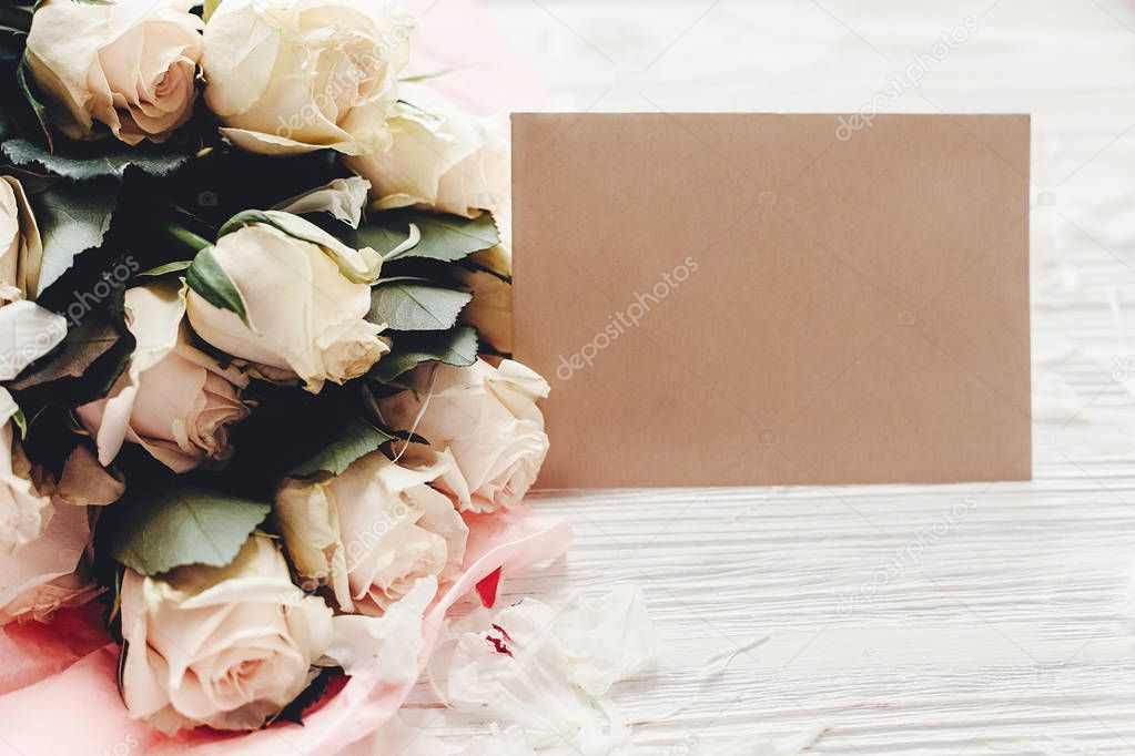 White roses with empty card on wooden background, space for text. Floral greeting card mockup. Wedding invitation,happy mother day concept. Valentine day
