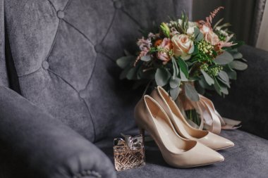 Modern düğün buket pembe gül ve pembe kurdele, bej Ayakkabı ve şık gri kanepe üzerinde parfüm şişesi ile yeşil okaliptüs. Düğün düzenlemelerin çağdaş kompozisyon