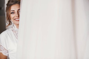 İpek elbise şık gelinlik odasında sabah holding içinde muhteşem gelin. Mutlu seksi gelin ve onun güzel gelinlik. Kadın gülümsüyor ve hazırlanıyor. Metin için yer.