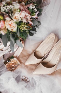 Modern düğün buket pembe gül ve yeşil okaliptüs, bej Ayakkabı ve yumuşak kumaş üzerine parfüm. Düğün, en iyi görünüm için şık gelin aksesuar çağdaş bileşimi