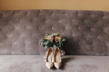 Modern düğün buket pembe gül ve şık gri kanepe üzerinde pembe kurdeleler, bej ayakkabı ile yeşil okaliptüs. Düğün için gelin aksesuar çağdaş bileşimi