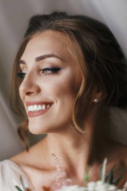 Muhteşem güzel gelin buketi yumuşak ışık penceresinde, poz ile. Mutlu gelin portre mükemmel makyaj, gülümseyerek ve hayal ile şık elbise. Romantik an. Metin için yer