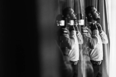 Şık damat beyaz gömlek ve papyon pencere ışıkta poz. Kendinden emin ve mutlu adam portresi. Damat sabah hazırlanıyor. Yaratıcı düğün fotoğraf ayna yansıması ile