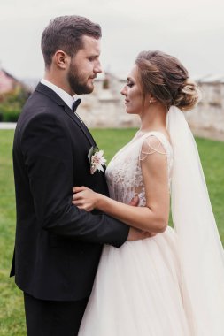 Muhteşem gelin ve yavaşça sarılma ve açık havada poz şık damat. Şehvetli düğün çifti kucaklayan. Yeni evliler romantik anlar. Düğün fotoğraf