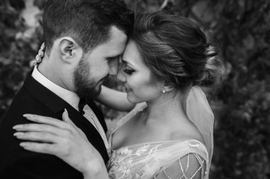 Muhteşem gelin ve yavaşça sarılma ve öpüşme açık havada şık damat. Şehvetli düğün çifti kucaklayan. Yeni evliler romantik anlar. Düğün fotoğraf
