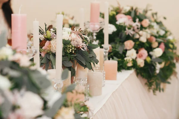 在餐厅举行的婚礼招待会上 时尚漂亮的花束配有玫瑰和蜡烛在柔和的桌子上 现代婚礼设置 婚礼安排和装饰 — 图库照片