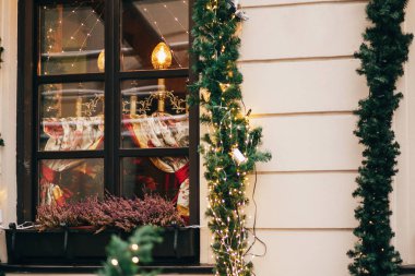 Şık Noel süsleri, garland ışıklar ve çam dalları ile Avrupa şehri sokak penceresinde süsler
