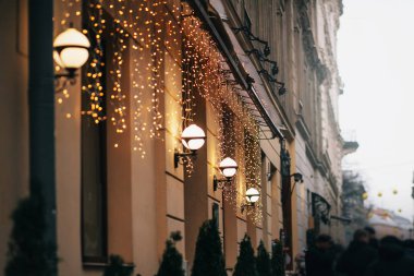 Şık Noel süslemeleri, garland ışıkları ve lambaları eski bina ve Avrupa şehir sokak insan kalabalığı. Festival dekor ve aydınlatma şehir merkezinde, kış tatil
