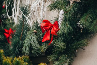 Şık Noel çelenk kırmızı yay ve süs eşyaları, çam kozalakları, yıldız ile Avrupa şehir sokak binada üzerinde beyaz dalları. Festival dekor şehir merkezi, kış tatili