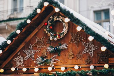 Şık garland ışıkları ve çam dalları ile Noel süslemeleri, çelenk, ağaç ve ahşap kabin Avrupa şehri Market yıldız süsler. Şenlikli sokak dekor kış tatilleri