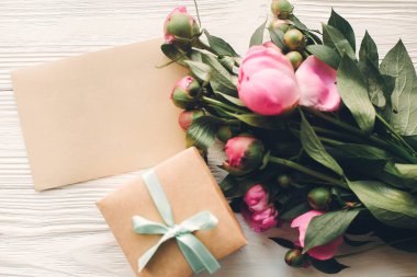 çok güzel pembe peonies boş el sanatları kartı ve hediye kutusu beyaz rustik ahşap arka plan üst görünümünde, metin için yer. çiçek tebrik kartı mock-up. mutlu anneler günü kavramı