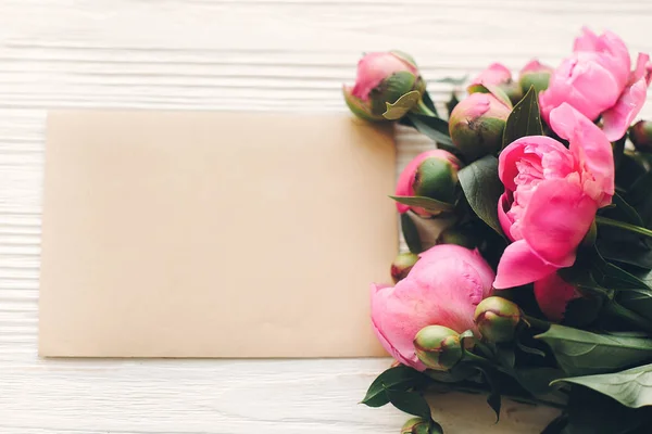 素朴な白い木製の背景の空のクラフト カードで素敵なピンクのシャクヤク平面図 テキスト用のスペースです 花のグリーティング カードのモックアップ 美しい花 幸せな母の日の概念 — ストック写真