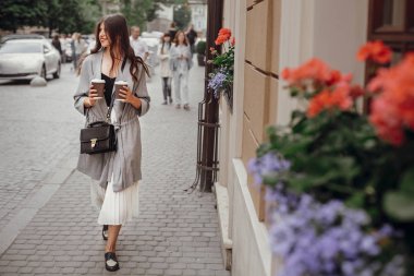 İki fincan gülümseyen ve şehir sokak yürüyüş kahve olan muhteşem kadın. Güzel saç ve şehirde vaktinizi mükemmel bir gülümseme ile şık mutlu hippi kız. Kopya alanı
