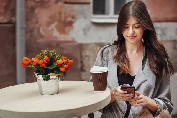 Hermosa Mujer Joven Sosteniendo Teléfono Taza Café Bolsa Mesa Madera —  Fotos de Stock