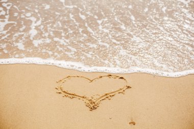 Deniz kenarında dalga ile kum plajındaki yazılı kalp. Aşk kavramı. Sevgililer günün kutlu olsun. Yeni evliler için balayı. Sevgililer günü. Metin için yer. İyi Bayramlar