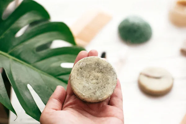 Doğal katı şampuan bar bambu fırça, deodorant arka plan üzerinde tutan el, Beyaz ahşap üzerine sünger