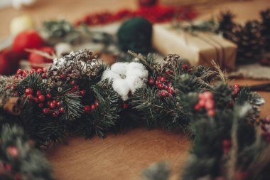 Rustik Noel çelenk ayrıntılarını, pamuk kapatın. Çam dalları ile kırmızı meyveler, çam kozalakları, şerit, rustik ahşap üzerine tarçın. Tatil Atölyesi'nde atmosferik moody görüntü