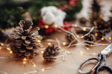Çam kozalakları, çam dalları, çelenk, kırmızı meyveler, Tel, makas, tarçın, pamuk, rustik ahşap arka plan ışığı. Noel çelenk Atölyesi'nde yapmak için ayrıntılar. Atmosferik görüntü