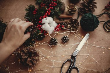 Çam dalları, çelenk, kırmızı meyveler, çam kozalakları, Tel, makas, tarçın, pamuk, rustik ahşap arka plan ışığı. Noel çelenk Atölyesi'nde yapmak için ayrıntılar. Atmosferik görüntü