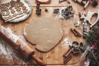 Noel zencefilli kurabiye yapma. Ahşap oklava, tarçın, anason, koniler, Noel süsleri ile rustik tabloda metal kesiciler ile hamur. Atmosferik şık görüntü