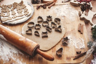 Noel zencefilli kurabiye yapma. Ahşap oklava, tarçın, anason, koniler, Noel süsleri ile rustik tabloda metal kesiciler ile hamur. Atmosferik şık görüntü