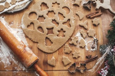 Noel zencefilli kurabiye düz yapma yatıyordu. Ahşap oklava, tarçın, anason, koniler, Noel süsleri ile rustik tabloda metal kesiciler ile hamur. Atmosferik görüntü