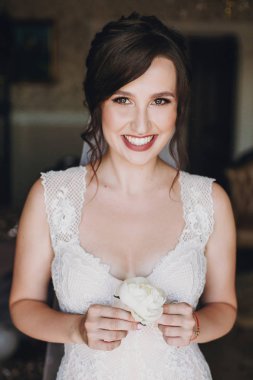 Beyaz şakayık yaka çiçeği elinde tutan ve gülümseyerek, damat için bekleyen şaşırtıcı elbise muhteşem gelin. Güzel bir kadın sabah hazırlanıyor. Düğün hazırlıkları