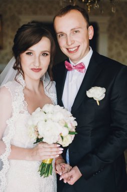 Muhteşem gelin şaşırtıcı elbise şık damat odası ile sabah poz. Güzel düğün çifti hazırlanıyor. Düğün hazırlıkları