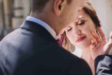 Muhteşem gelin ve yavaşça sarılma ve güneşli sokakta kucaklayan şık damat. Güzel mutlu evlilik çift portreleri. Romantik duygusal an dokunmatik. Gerçek aşk