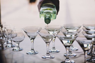 Garson düğün partide tablo üzerinde kristal bardaklarda dökme martini. Martini satır alkol barda içecekler. Noel ve yeni yıl Bayramı. Kutlamalar ve parti konsept.