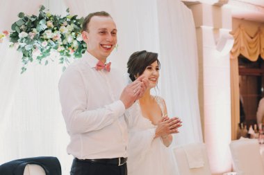 Muhteşem gelin ve gülümseyen ve eller merkezinde Restoran düğün resepsiyonunda, alkışlar şık damat. Düğün çift alkış